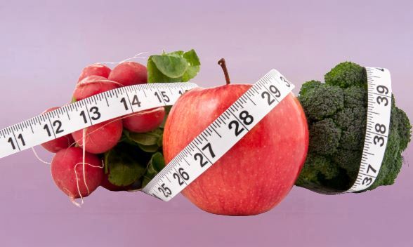 fruits on purple background with measuring tape used for weight loss wrapped around them